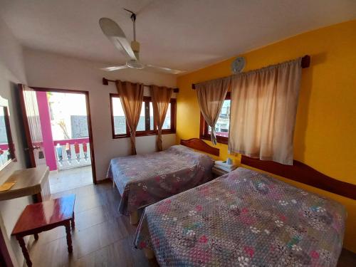 a bedroom with two beds and a table and windows at Posada Casa Bugambilias in Tecolutla
