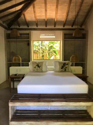 a bedroom with a large white bed with a window at Casa Das Águas Trancoso in Trancoso