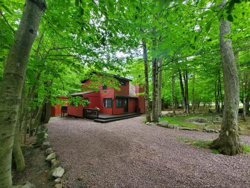 a red house in the middle of a forest at Chalet renovated Near Casino, Camelback , Kalahari 4bdrms firepit hot tub game room in Tobyhanna