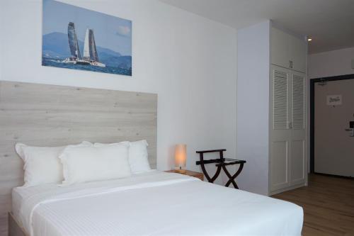 a bedroom with a large white bed with a picture on the wall at Ramada by Wyndham Langkawi Marina in Kuah