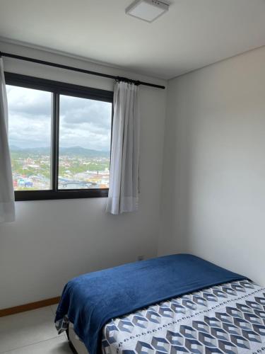 a bedroom with a bed and a large window at Apartamento novo frente mar com piscina em Home Club in Penha