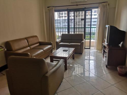 a living room with couches and a tv and a table at Marina Court KK City Homestay in Kota Kinabalu
