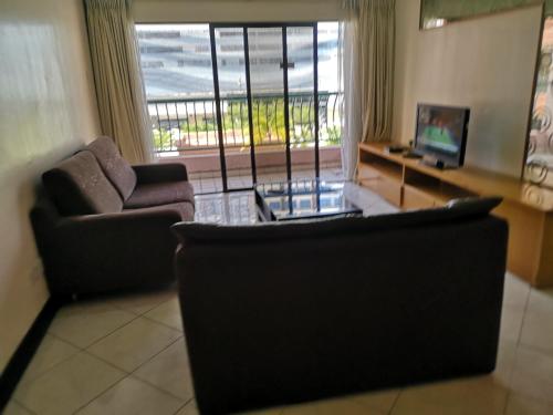 a living room with two couches and a television and a balcony at Marina Court KK City Homestay in Kota Kinabalu