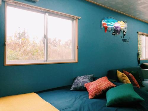 ein Schlafzimmer mit einer blauen Wand und einem Fenster in der Unterkunft 恩納村名嘉真フォレストヴィラ12時チェックアウト可ダブルベッド2台と2段ベッドとユニットバス2室 in Onna