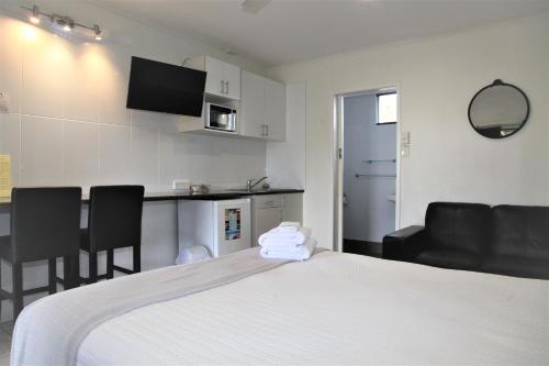 a hotel room with a bed and a kitchen with chairs at Charm City Motel in Bundaberg