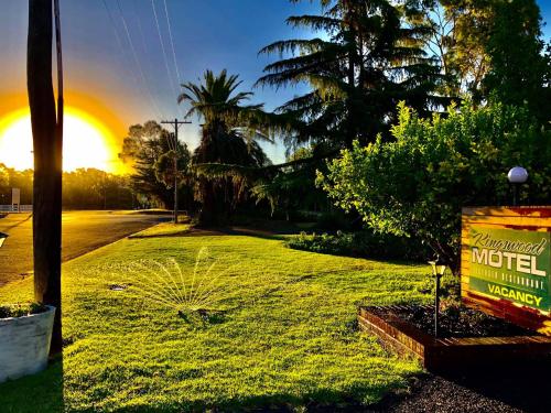 un segno nell'erba con un tramonto sullo sfondo di Kingswood Motel a Tocumwal