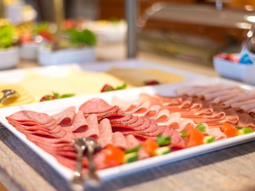 a tray of meats and vegetables on a table at ACHAT Hotel Schwarzheide Lausitz in Schwarzheide