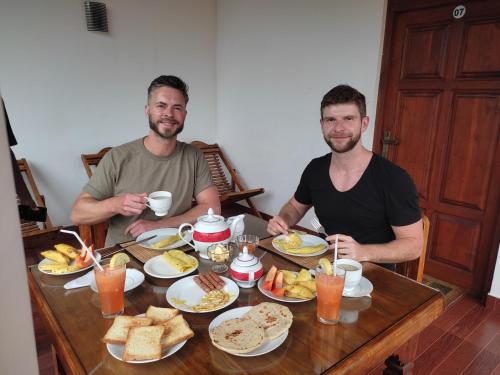 two men sitting at a table with breakfast food at Freedom Guest Inn Ella in Ella