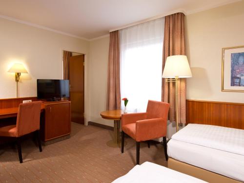 a hotel room with a bed and a desk and a television at ACHAT Hotel Schwarzheide Lausitz in Schwarzheide