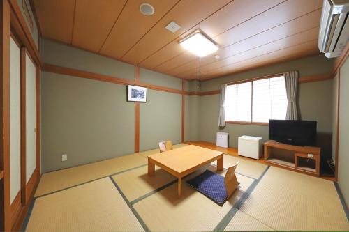 a living room with a table and a tv at Smile Hotel Takaoka Ekimae in Takaoka