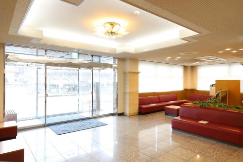 a lobby with red couches in a building at Smile Hotel Takaoka Ekimae in Takaoka