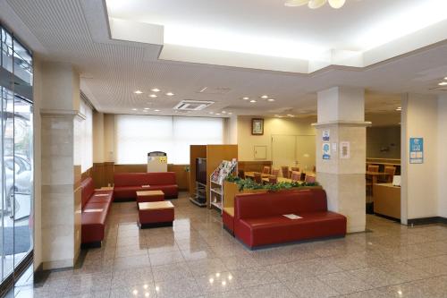 a lobby with couches and tables in a building at Smile Hotel Takaoka Ekimae in Takaoka