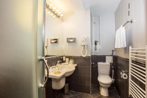 a bathroom with a sink and a toilet and a mirror at Europe Hotel in Sofia