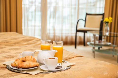a tray of food and orange juice and croissants on a bed at Europe Hotel in Sofia