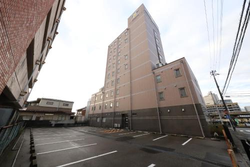 a tall building in the middle of a street at Smile Hotel Takaoka Ekimae in Takaoka