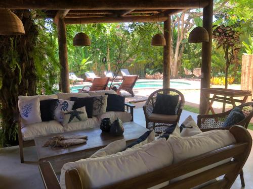 a living room with couches and a table and chairs at Casa Das Águas Trancoso in Trancoso
