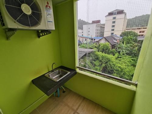 a green room with a sink and a window at The Peak Songkhla in Ban Khao Rup Chang