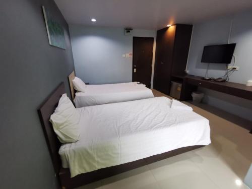 two beds in a hotel room with a television at The Peak Songkhla in Ban Khao Rup Chang