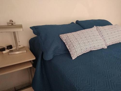 ein blaues Bett mit einem Kissen und einem Nachttisch in der Unterkunft Zona nuevo CAMPUS Universidad departamento independiente in Chihuahua