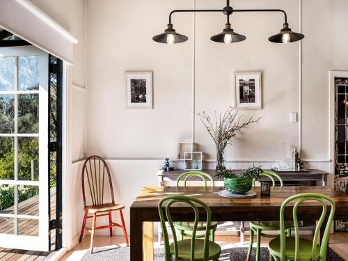 uma sala de jantar com uma mesa de madeira e cadeiras verdes em Table Hill Cottage em Daylesford