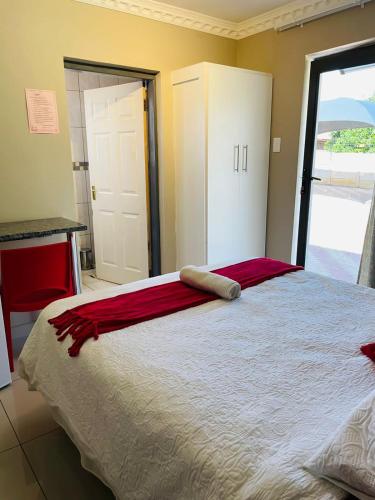 um quarto com uma cama grande e um cobertor vermelho em ONNIE GUESTHOUSE em Louis Trichardt