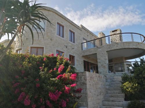 a stone house with a palm tree and flowers at Castle On The Heads in Knysna
