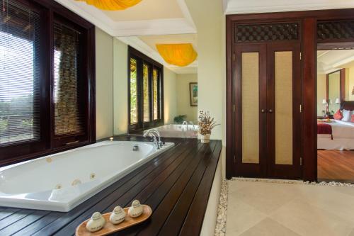 a large bathroom with a tub and a bedroom at Anhera Suite Ubud in Ubud