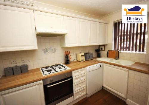 a kitchen with white cabinets and a stove top oven at 4 Bed Townhouse/Free Parking in Mitcham