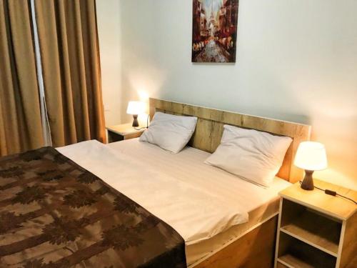 a bedroom with a bed with two night stands and two lamps at vake in Tbilisi City