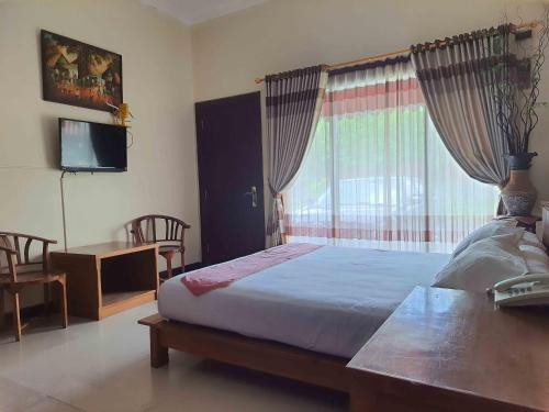 Schlafzimmer mit einem Bett, einem TV und einem Fenster in der Unterkunft Omahkoe Syariah Guesthouse RedPartner in Seturan