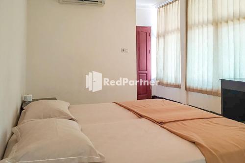 a bed sitting in a room with a window at Palu City Guest House Mitra RedDoorz in Palu