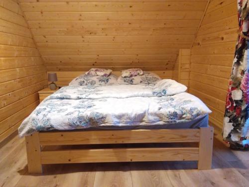 ein Schlafzimmer mit einem Bett in einem Holzzimmer in der Unterkunft Domek na wzgórzu ''NIEDŹWIEDŹ'' in Świątkowa Mała