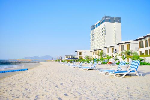 eine Reihe von Chaiselongues am Strand in der Unterkunft Mirage Bab Al Bahr Beach Resort in Dibba