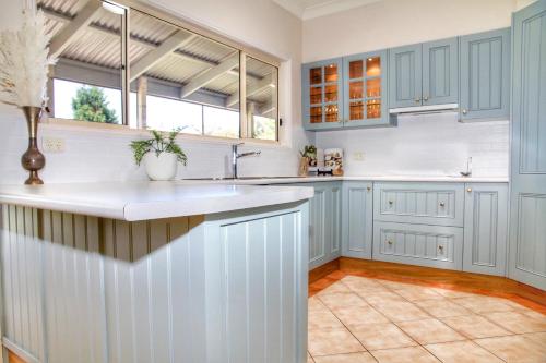 a kitchen with blue cabinets and white counter tops at Marigold Cottage, A Blue Mountains Oasis- Spacious, Views & Kangaroos in Little Hartley