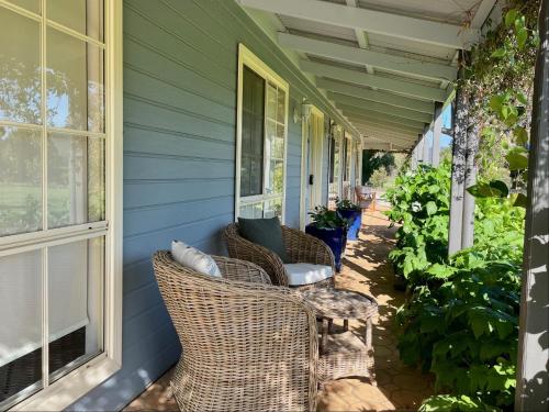 a porch with wicker chairs on a blue house at Marigold Cottage, A Blue Mountains Oasis- Spacious, Views & Kangaroos in Little Hartley