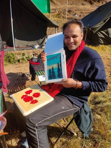 a man sitting in a chair holding a laptop at Dhanaulti Camp Homes Retreat in Dhanaulti