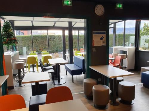 a restaurant with tables and chairs and a clock at ibis budget Clermont Ferrand Sud in Aubière