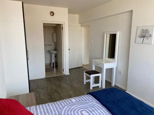 a bedroom with a bed and a desk and a sink at Tenbury Beach Apartment in Durban