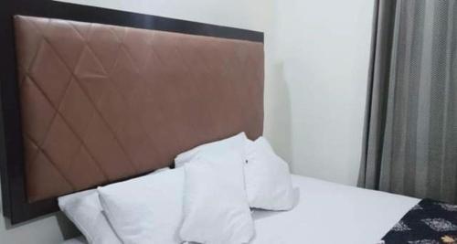 a bed with white pillows and a brown headboard at Family Guest House Lahore Near Airport in Lahore