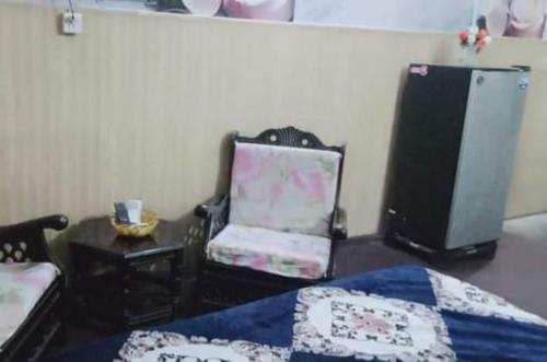a bedroom with a bed and a chair and a refrigerator at Family Guest House Lahore Near Airport in Lahore