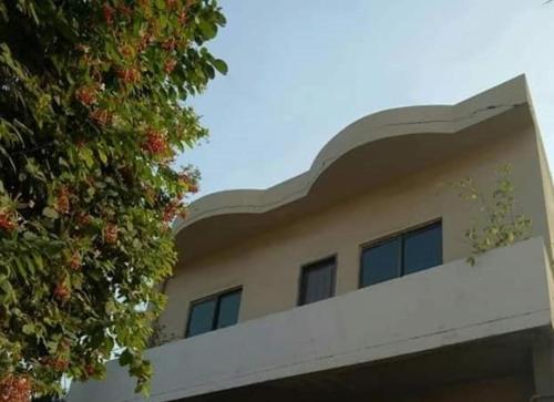 a building with a tree next to it at Family Guest House Lahore Near Airport in Lahore