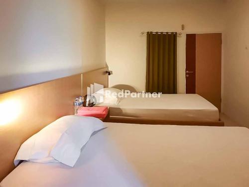 ein Hotelzimmer mit einem Bett und einem großen Bett sidx sidx sidx sidx in der Unterkunft Wisma Baznas Syariah Majalengka Mitra RedDoorz in Majalengka