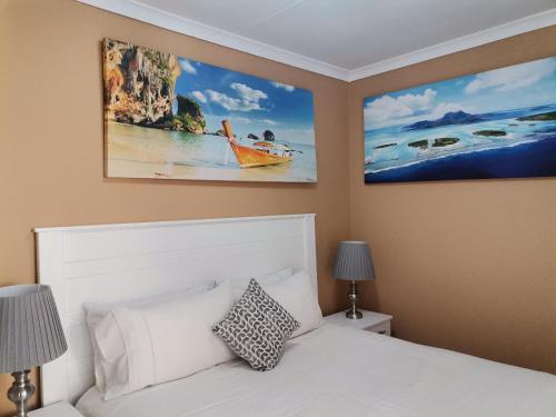 a bedroom with a white bed with two pictures on the wall at Onyx on Sycamore in Cape Town