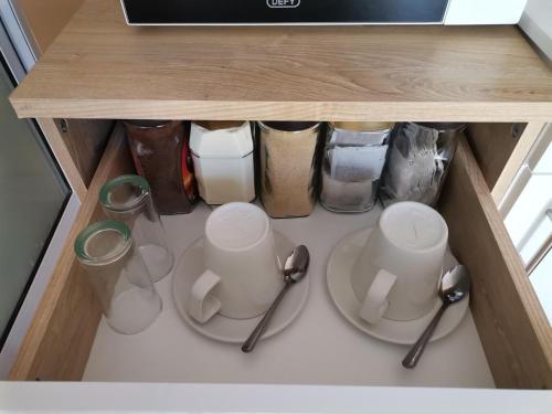 a cabinet with two plates and cups and utensils at Onyx on Sycamore in Cape Town