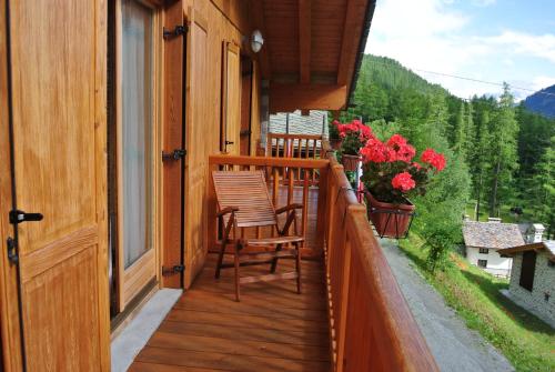 un balcón con 2 sillas y flores en una casa en Hotel de Gletscher en Gressoney-la-Trinité
