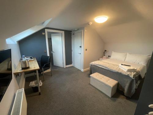 um pequeno quarto com uma cama, uma secretária e uma mesa em Arlan House, Central Basingstoke Hotel em Basingstoke