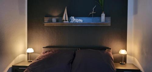 a bedroom with a bed with two lamps and a shelf at Ferienwohnung Flensfjord in Wees
