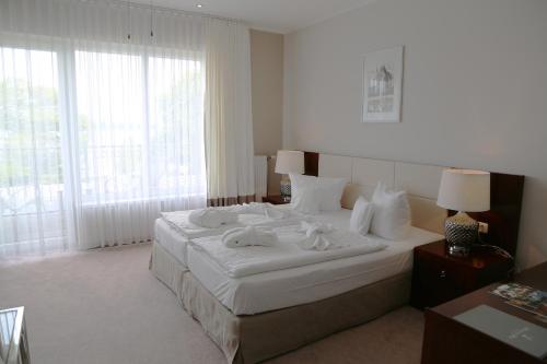 a bedroom with a large white bed with towels on it at Hotel Resort Märkisches Meer in Diensdorf-Radlow
