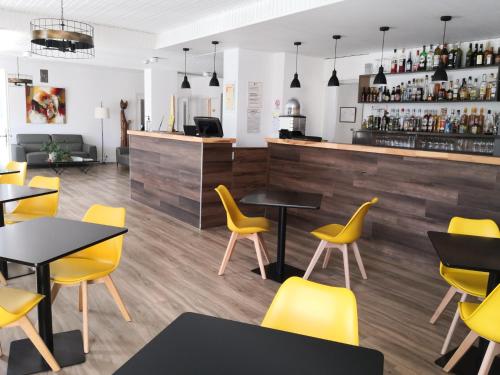 a restaurant with yellow chairs and tables and a bar at Logis Hôtel-Restaurant Le Tanargue in Valgorge