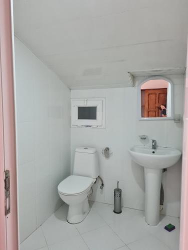 a white bathroom with a toilet and a sink at Merabi Guest House in Makhinjauri